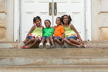 Happy siblings sitting on church steps