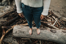barefoot woman standing on a log 