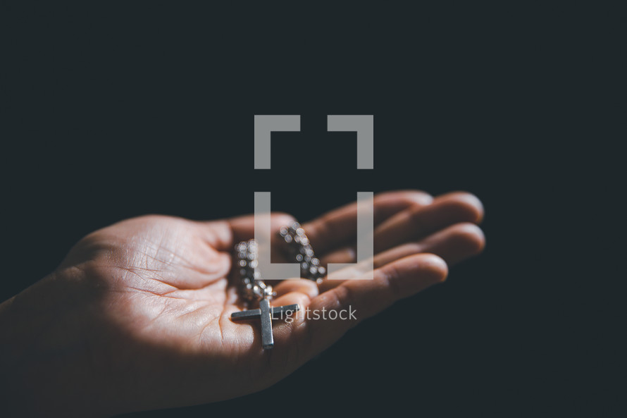 Hand holding a silver cross necklace