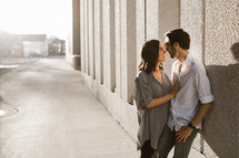 a couple kissing on a sidewalk 