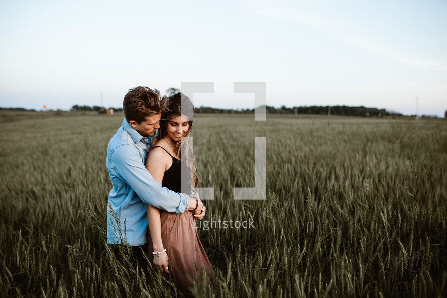 a couple snuggling in a field of wheat 