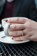 a woman with hand on a mug with engagement ring 