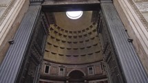 Entrance door to pantheon view of pantheon ceiling spinning sun rays coming through the hole in Rome city italy.