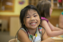 A young girl smiling in a classroom