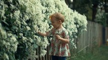 a toddler girl picking flowers 