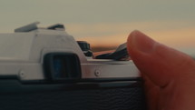 A man's hand flicks the trigger of a film camera
