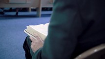 person with a Bible on their lap during a worship service 