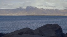 snow on mountains at the edge of a shore 