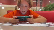 Child on a phone in a restaurant