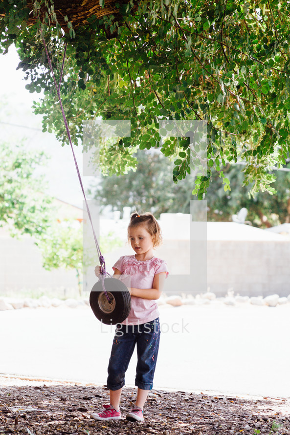 a girl child playing with a tire swing 