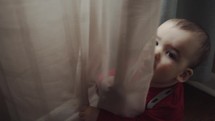 toddler playing in curtains 