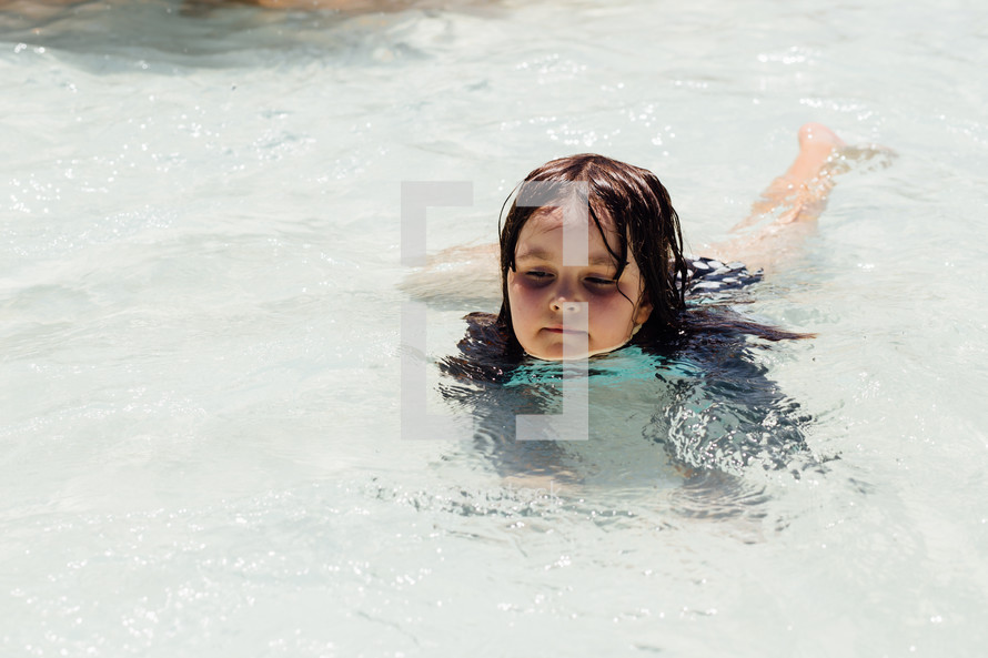 a little girl wadding in shallow pool water 
