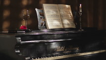Romantic atmosphere with music sheet, red rose and glass of champagne on the old piano. 