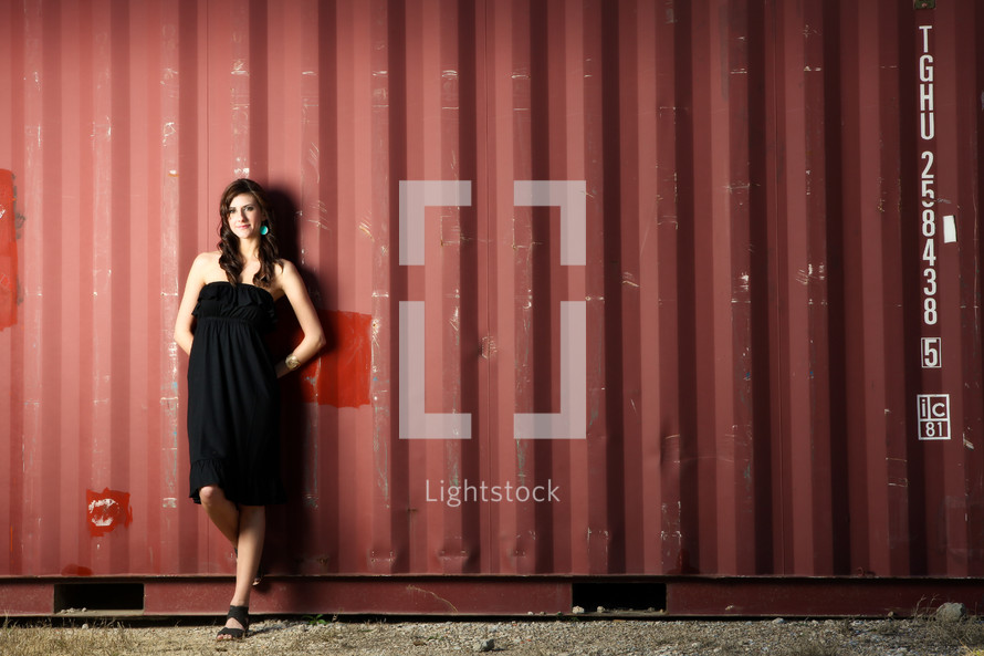 woman in a black dress standing in front of a warehouse 