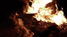 Dramatic, cinematic, slow motion fire and flames engulfing a pile of wood in camp fire.