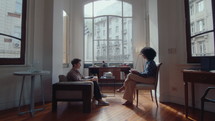 Young woman speaking with female therapist, answering her question during counseling session in the office. Side view, zoom shot
