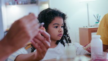 African-American senior grandmother, her daughter and little granddaughter eating jam toasts on breakfast at home, smiling and talking, spending time together at home
