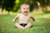 Laughing baby sitting on the grass
