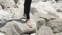 walking barefoot on rocks along a shore 