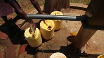 filling water jugs at a well 