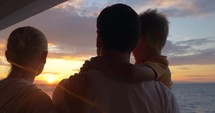 Parents with child looking at sunset and taking selfie