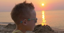 boy in sunglasses on the beach at sunset
