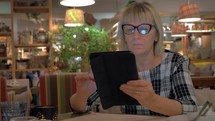 Senior woman browsing on touch pad in cafe