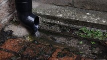 Water Flowing Out of Drain Pipe Into an Ancient Drain