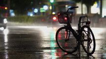 Chained up bike with cars driving by in the rain