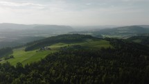 aerial of a hill with grass and forest in rural switzerland
