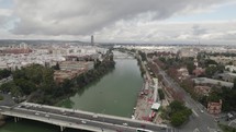 Panoramic cityscape from over Guadalquivir river of Seville, Spain; drone
