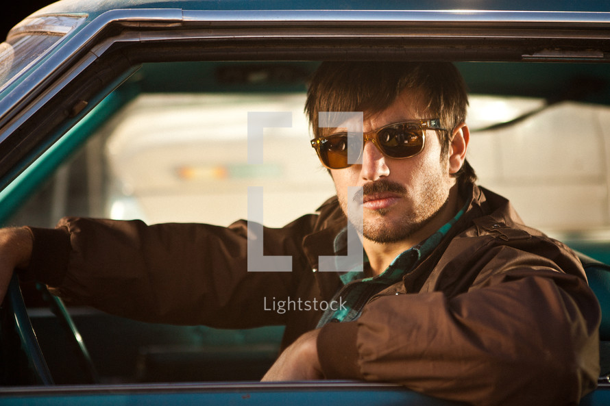 man in sunglasses looking out of a car window