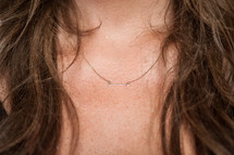 Gold arrow necklace on a neck.