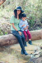 Mother and son sitting on log over river