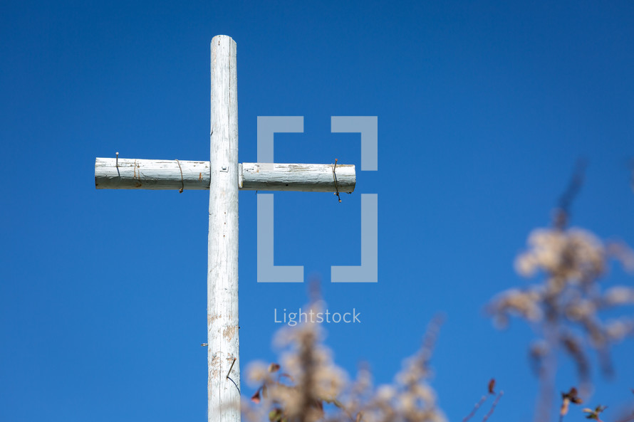 Rustic painted wooden cross with nails in garden 