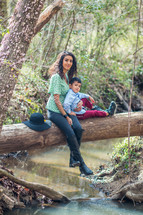 Mother and son sitting on log over river