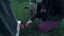 a girl putting flowers on a grave 