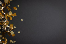 Gold streamers and confetti on a black background with copy space