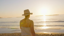 Steadycam shot of a Young attractive woman walking on the beach during sunset