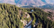 Aerial, orbit, drone shot, around a road and Romanian spruce forest, on a mountain, on a sunny, fall day, in Romania
