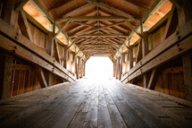 Wooden covered bridge leading to bright opening