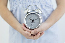 cupped hands holding an alarm clock 