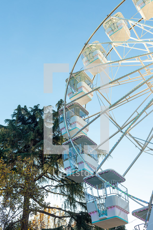 Ferris wheel on the blue sky background. Attraction present in amusement parks.