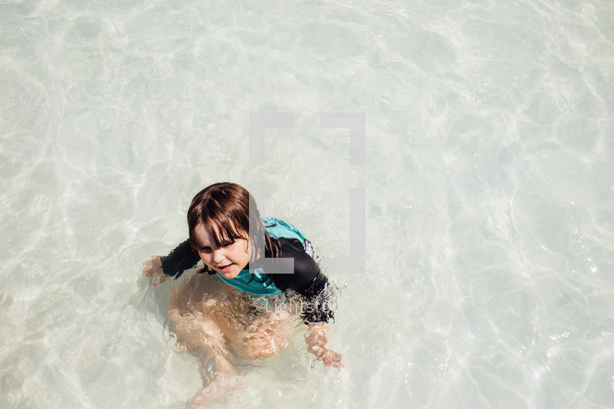 a little girl wading in shallow pool water 