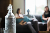 glass bottle and people sitting on a couch 