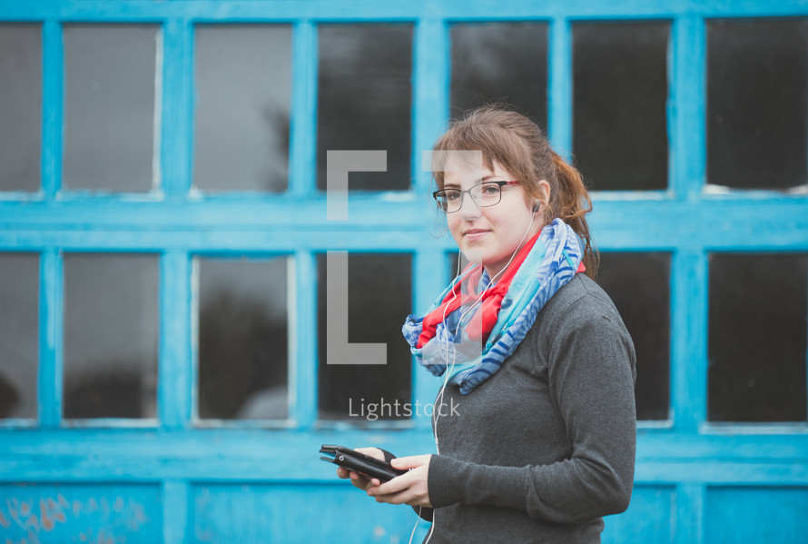 a woman holding a tablet and listening to earbuds 