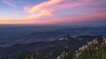 Clouds coloured in pastel colours at sunset. Mountain landscape with forests and rocky peaks. Autumn landscape, timelapse

