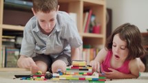Two kids building with toy bricks at home