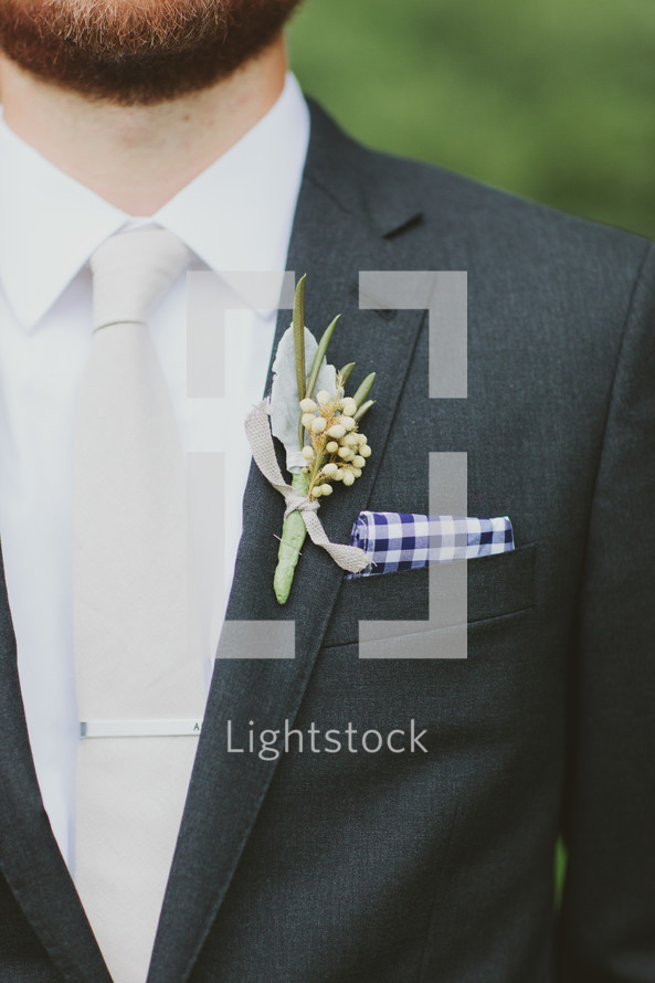 Bearded man with corsage on his jacket lapel.