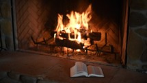 flames in a fireplace and open Bible 